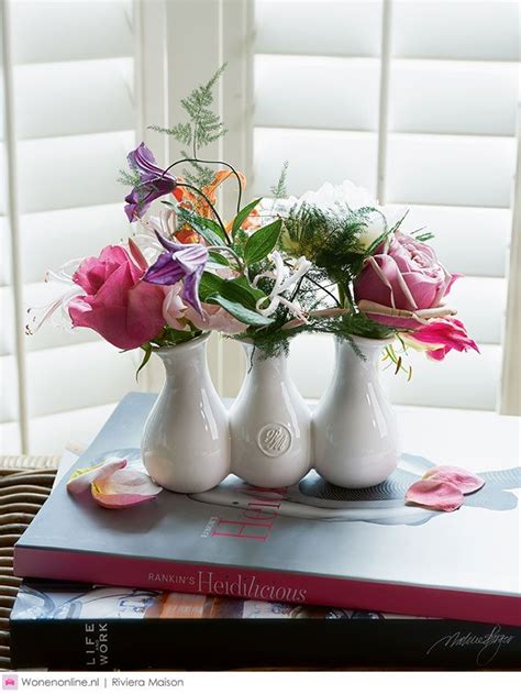 Three White Vases With Pink And Purple Flowers In Them On Top Of A Book