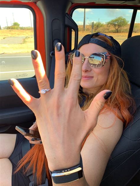 A Woman Sitting In The Back Seat Of A Car With Her Hand Up To The Camera