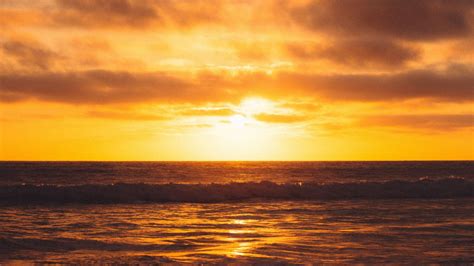 Download Wallpaper 1366x768 Sunset Sun Glare Water Clouds Tablet