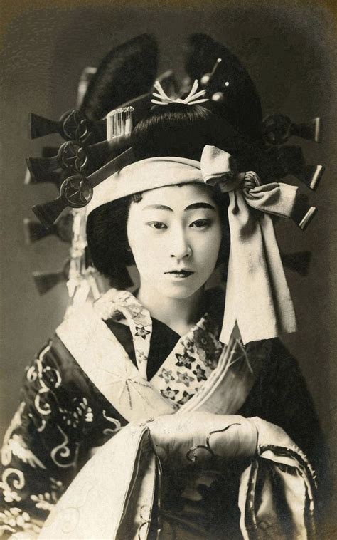 an old black and white photo of a woman in traditional japanese dress with her hands on her head