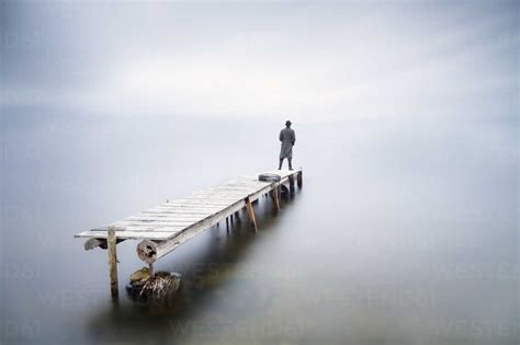Back View Of Man Standing On Jetty Watching Looking At Distance Stock Photo