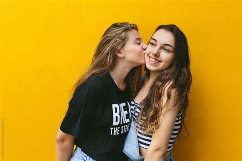 Teen Girls Kissing Over Yellow Background By Stocksy Contributor VICTOR TORRES Stocksy