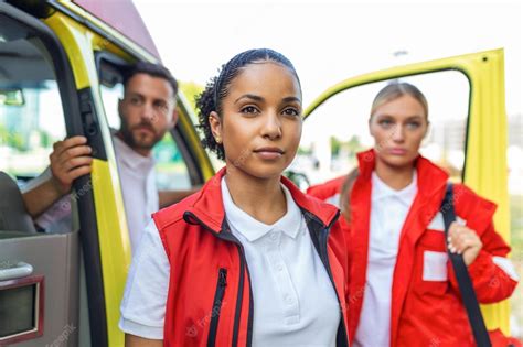 trois ambulanciers paramédicaux multiraciaux debout devant un véhicule ambulancier transportant