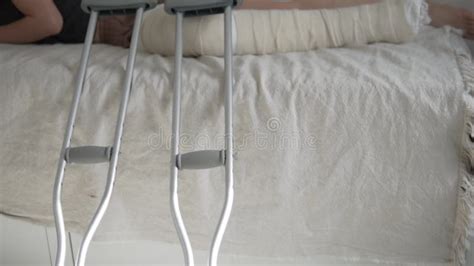 A Woman With A Broken Leg In A Cast Slowly Walks On Crutches On The