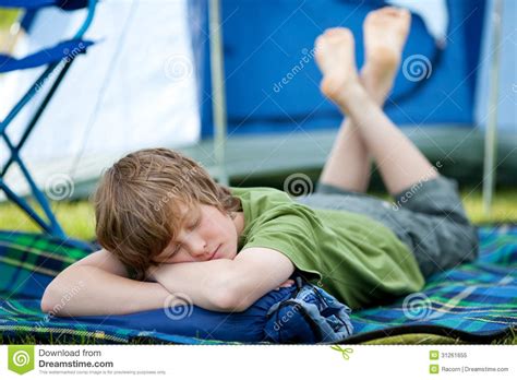 Boy Sleeping On Sleeping Bag With Tent In Background Stock