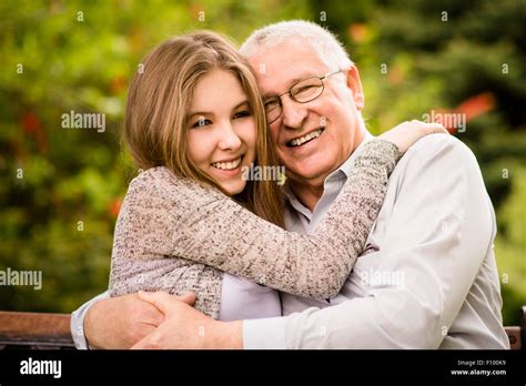 Happy Grandfather Hugging With His Teenage Granddaughter Outdoor In