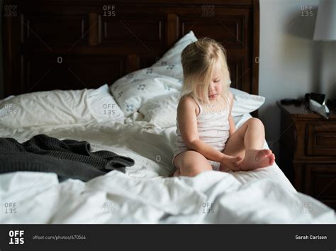 Little Girl Sitting On Bed Contemplating Her Foot Stock Photo Offset