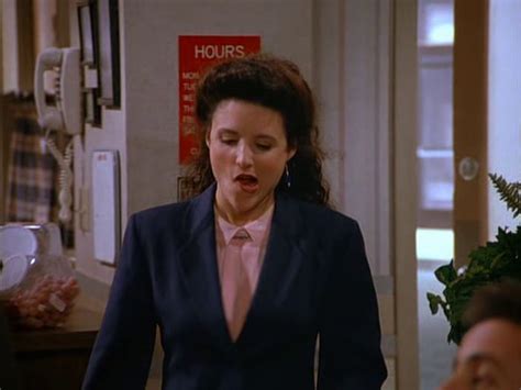 A Woman In A Blue Suit And Pink Shirt Is Walking Down The Hallway With