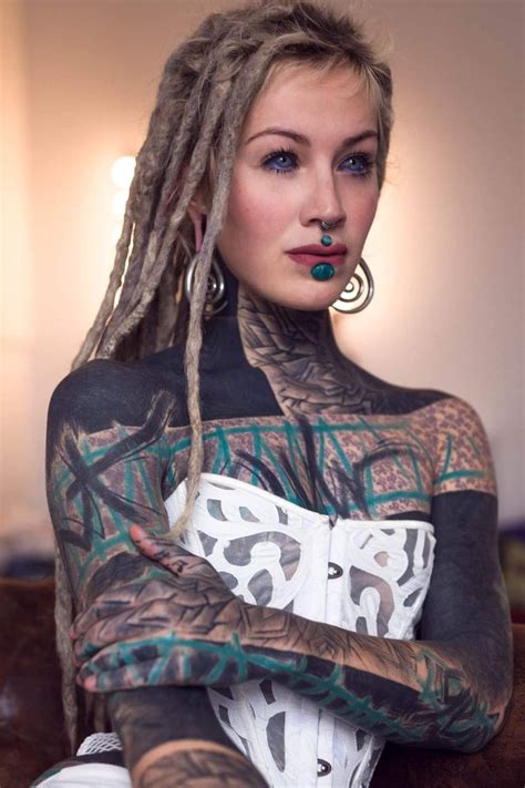 A Woman With Dreadlocks And Tattoos On Her Body Is Posing For The Camera