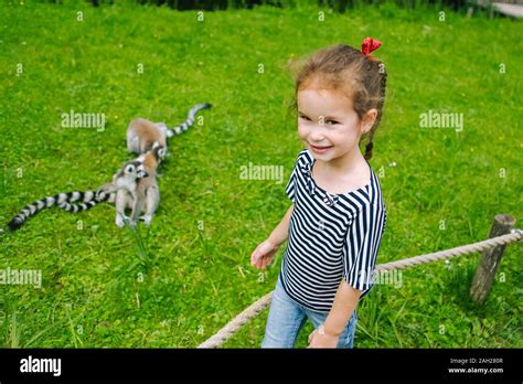 A Young Girl With Curly Braun Hair Having Fun With Ring Tailed Lemur