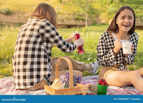 Two Young Teenage Girls On A Picnic Eating Drinking Lemonade Having Fun Laughing Talking