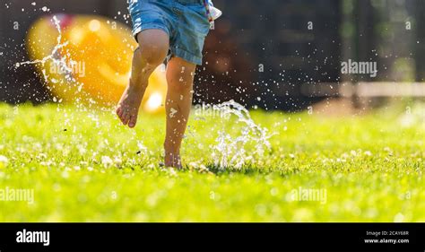 Happy Child Running Through Wet Lawn Splashinh Water Stock Photo Alamy