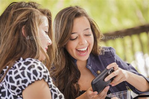 Mixed Race Girls Talking While Using Electronic Devices Stock Photo By