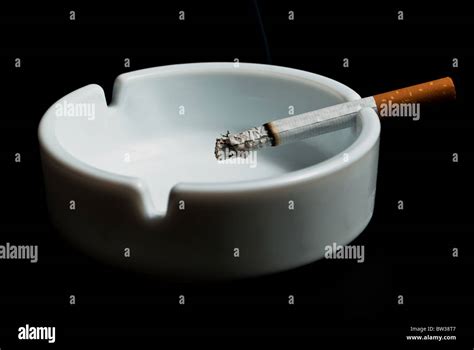 Burning Cigarette In The Ashtray White On Black Background Stock Photo