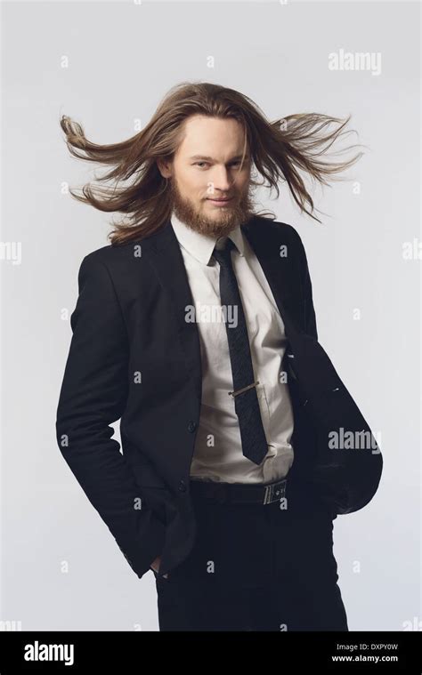 A Bearded Man Male Model Long Hair Posing In A Black Suit And Necktie