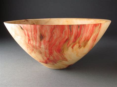 A Red And Yellow Bowl Sitting On Top Of A Gray Table Next To A Black Wall
