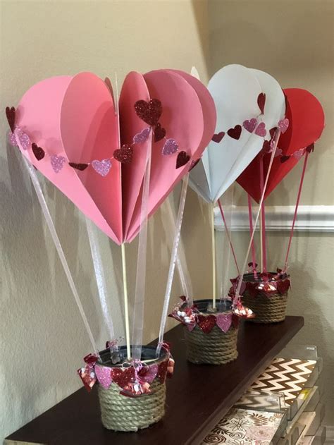 Three Heart Shaped Balloons Are Sitting In Small Baskets On A Shelf Next To A Wall