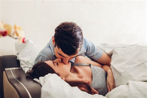 Pareja de enamorados besándose acostado en la cama por la mañana Foto Premium
