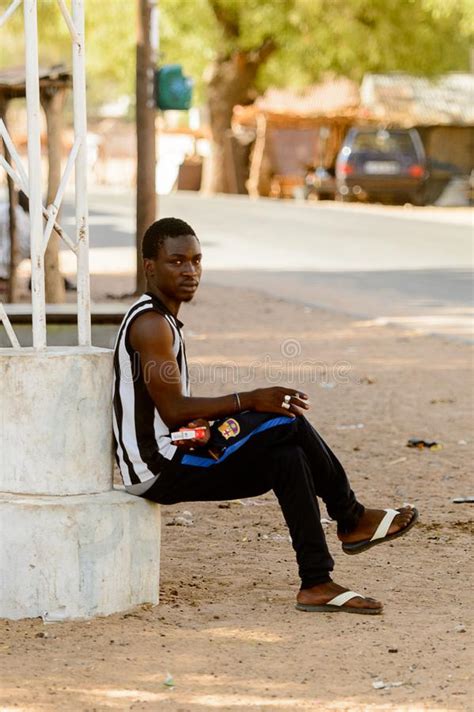 Unidentified Senegalese Man Sits On The Border Near The Road Editorial