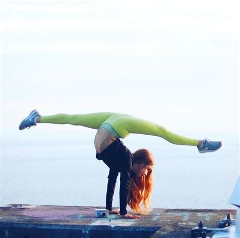a woman doing a handstand on top of a dock next to the ocean