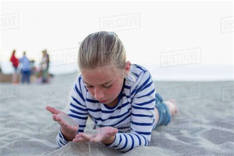 Girl Playing With Sand While Lying At Beach Stock Photo Dissolve