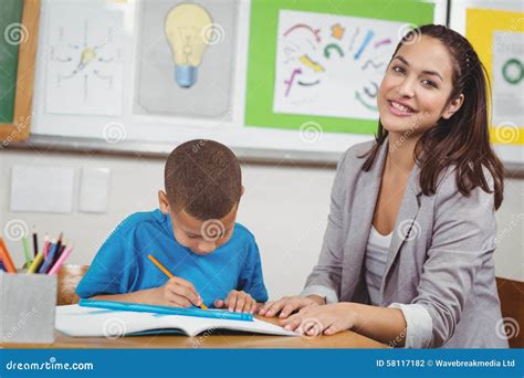 Alumno De Ayuda Del Profesor Bonito En Su Escritorio Foto De Archivo