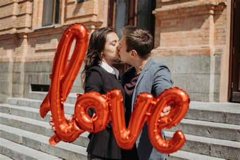 Premium Photo Couple Holding Balloon Kissing Outdoors