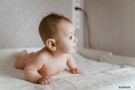 The Baby Is Lying On Its Stomach And Looks Into Stock Photo Crushpixel