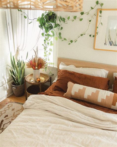 A Bed With Pillows And Blankets In A Bedroom Next To A Potted Houseplant
