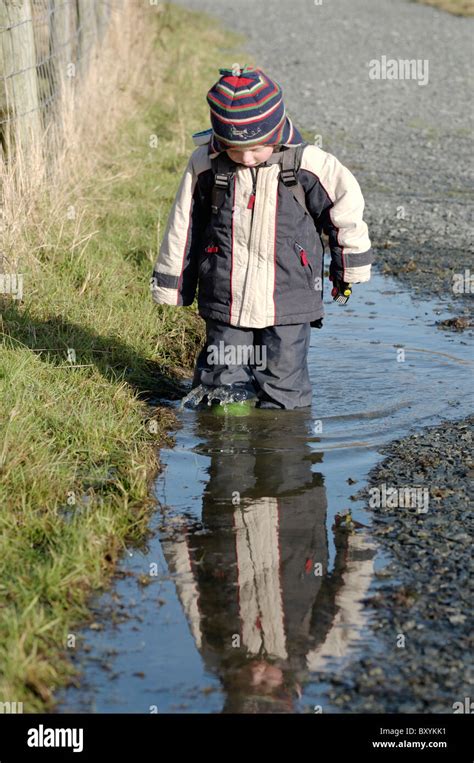 A Boy Walking Through A Puddle On A Country Walk Stock Photo Alamy