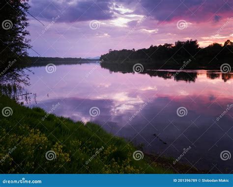 Summer Landscape Of The River With The Reflection Of Gloomy Clouds From