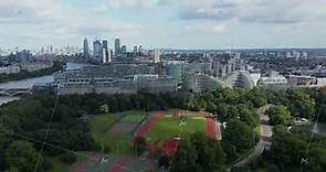 Slide and pan footage of Millennium Arena and tennis courts in Battersea Park at Thames river