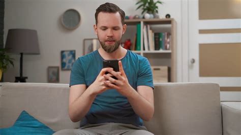 Man using his mobile smartphone on his sofa in his house.
