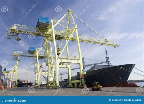 A large ship being unloaded by cranes at a busy port